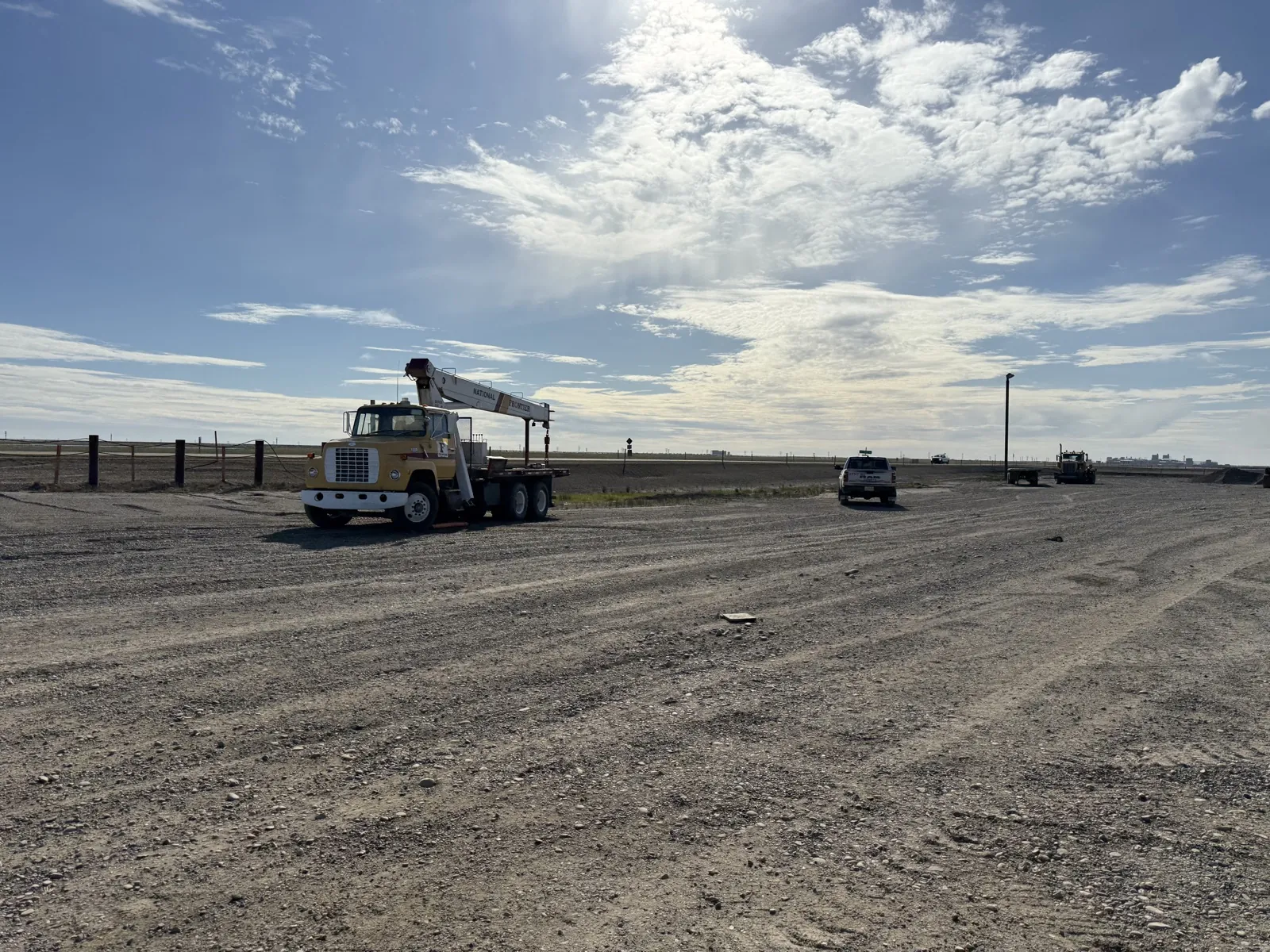 Open gravel pad and yard at Frontier with a crane truck under blue sky